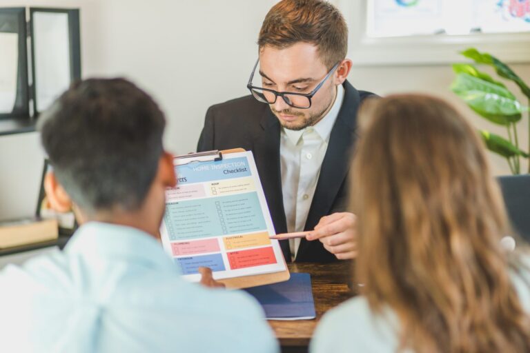 Professional man in suit showing home inspection checklist to couple in office.