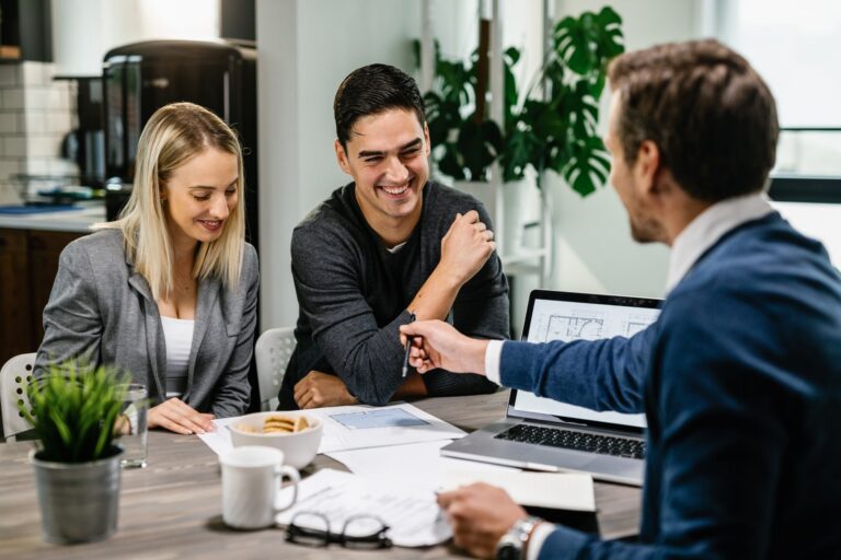 Three professionals, two men and one woman, discussing architectural plans at a modern office table.