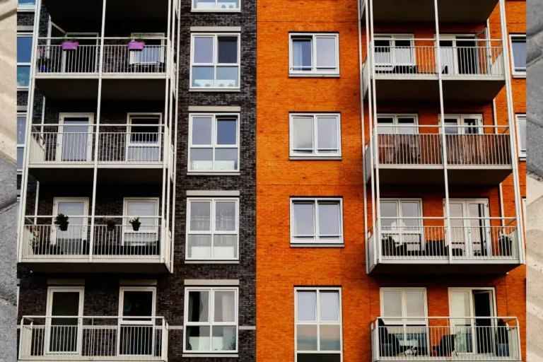 Modern apartment building facade with orange and dark brick walls and white balconies.