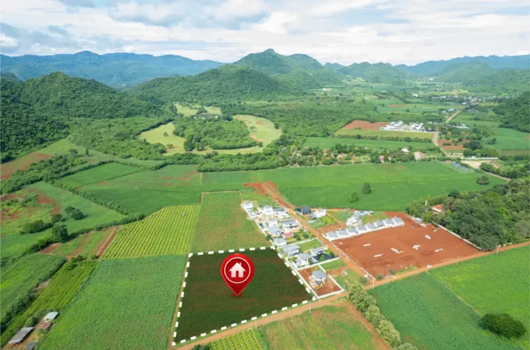 Aerial view of green agricultural fields and hills with a marked plot and house icon.