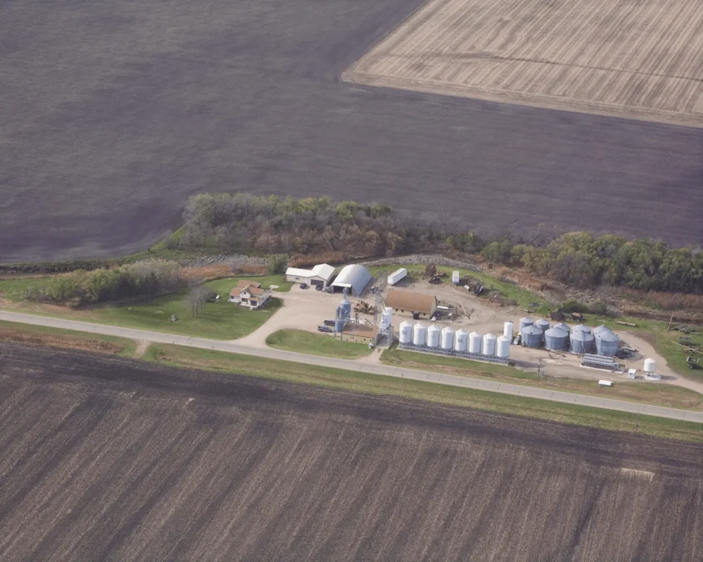 Aerial view of a rural farm with silos, buildings, and surrounding farmland.